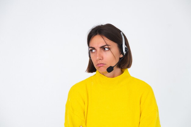 Mooie vrouw in gele trui op witte manager met koptelefoon ongelukkig moe verveeld?