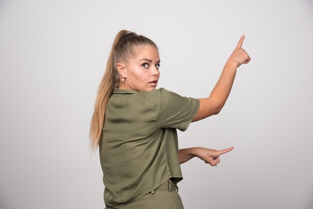 Mooie vrouw in groene jas ergens wijzen.