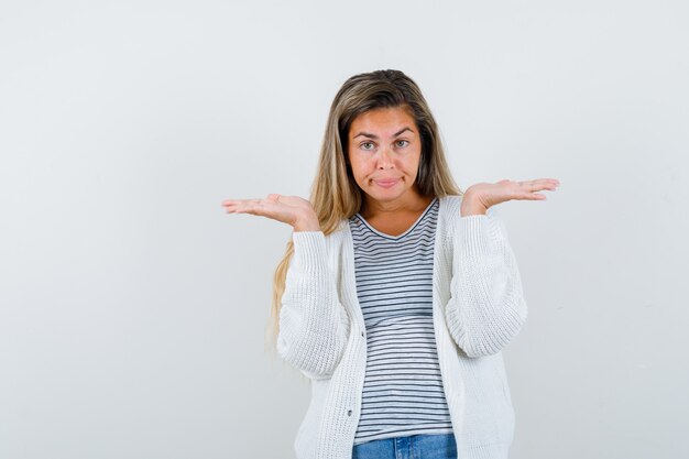 Mooie vrouw in jas die palmen uitspreidt en zelfverzekerd, vooraanzicht kijkt.