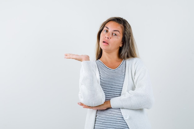 Mooie vrouw in jasje met welkom gebaar en op zoek verrast, vooraanzicht.