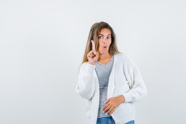 Mooie vrouw in jasje wijzende vinger en op zoek verrast, vooraanzicht.