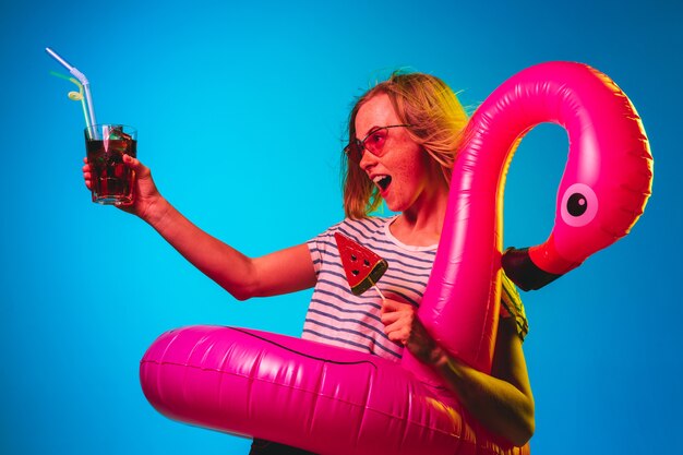 Mooie vrouw in neonlicht geïsoleerd op blauwe muur