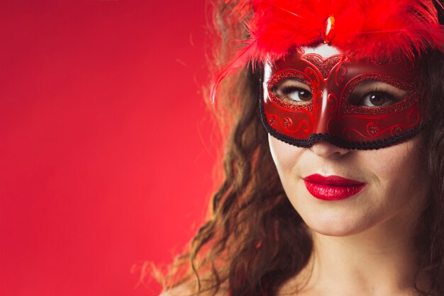 Mooie vrouw in rood masker met veren