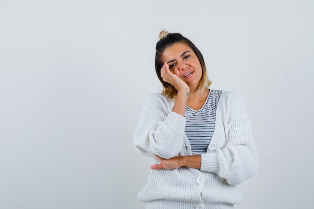 Mooie vrouw in t-shirt, vest leunt met wang op handpalm en ziet er verstandig uit