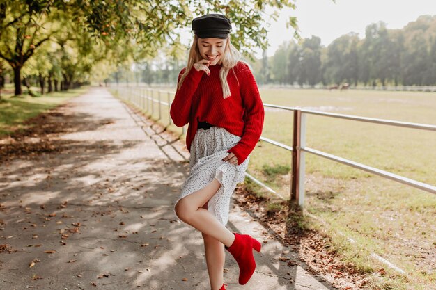 Mooie vrouw in trendy rode schoenen die zich voordeed op het parkpad Blond meisje met plezier buiten