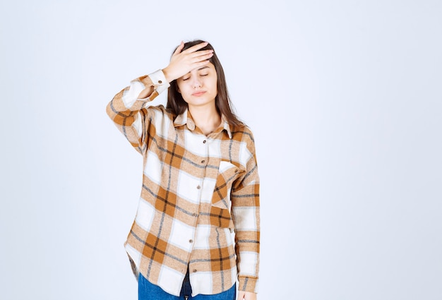 Mooie vrouw in vrijetijdskleding die zich op witte muur bevindt.