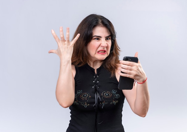 Mooie vrouw in zwarte blouse boos kijken naar de telefoon doet haar arm