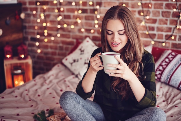 Mooie vrouw koffie drinken in haar slaapkamer