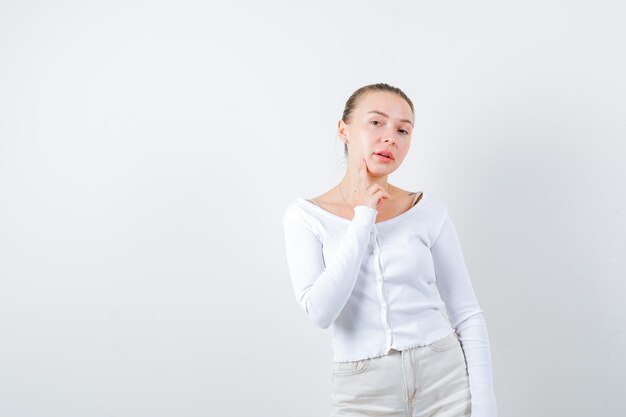 Mooie vrouw legt haar vinger op haar wang op witte achtergrond