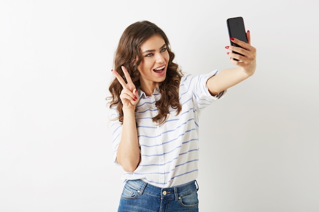 Mooie vrouw met grappige gezichtsuitdrukking selfie foto maken op mobiele telefoon, glimlachen, gelukkig, geïsoleerde, krullend haar, positieve stemming, student hipster stijl