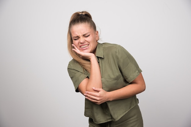 Mooie vrouw met kiespijn op grijze muur.