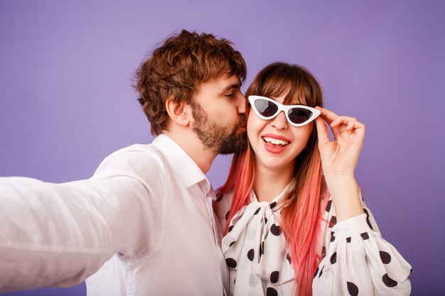 Mooie vrouw met openhartige glimlach en roze haar poseren met haar vriendje met baard