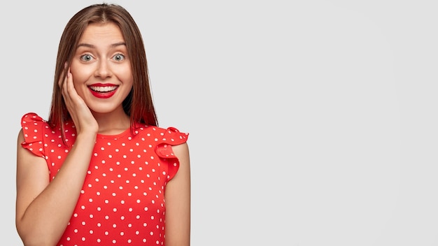 Mooie vrouw met rode lippenstift poseren tegen de witte muur