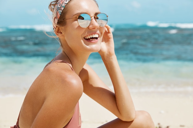 Mooie vrouw met zonnebril en zwempak op het strand