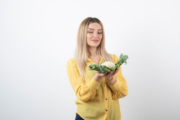 mooie vrouw model staan en kijken naar bloemkool.