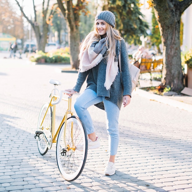 Mooie vrouw poseren in de buurt van fiets in park
