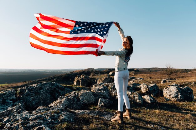 Mooie vrouw poseren met de Amerikaanse vlag op de top van de berg