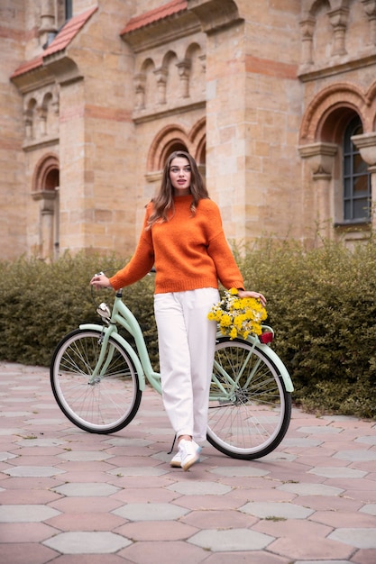 Mooie vrouw poseren met fiets en bloemen buitenshuis