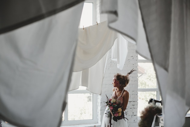 Mooie vrouw staat met een boeket onder opknoping wasserij in de kamer