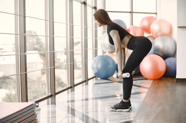 Gratis foto mooie vrouw voert roemeense deadlift uit in de sportschool. geschikte vrouw die gewichtheffen uitvoert. het dragen van zwart kostuum.