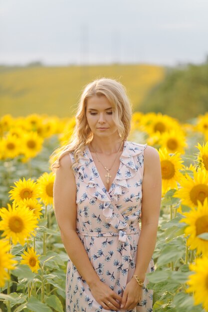 Mooie vrouw vormt op het landbouwgebied met zonnebloem op een zonnige zomerdag