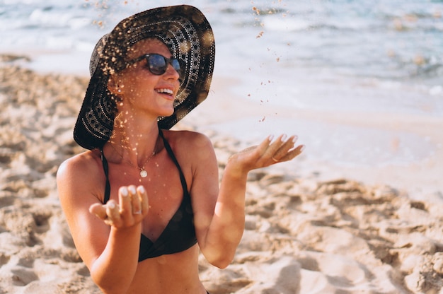 Mooie vrouw zittend op zand door de oceaan