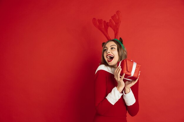 Mooie vrouw zoals kerst herten geïsoleerd op rode muur