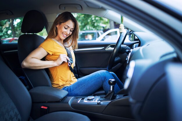 Mooie vrouwelijke bestuurder veiligheidsgordel zetten alvorens een auto te besturen