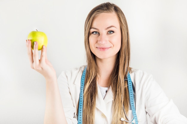 Mooie vrouwelijke diëtist die groene appel houdt