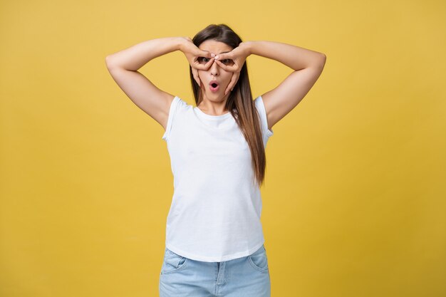 Mooie vrouwelijke halve lengte portret geïsoleerd op gele studio achtergrondgeluid. de jonge emotionele glimlachende en verraste vrouw die staat en naar de camera kijkt. de menselijke emoties, gezichtsuitdrukking concept.