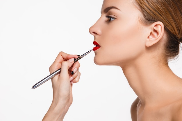 Mooie vrouwelijke lippen met make-up en penseel op wit. Make-up artiest werkproces