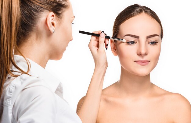 Mooie vrouwelijke ogen met make-up en penseel op wit. Make-up artiest werkproces