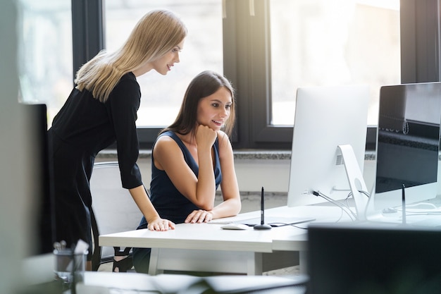 Mooie vrouwen die in het bureau aan een computer samenwerken