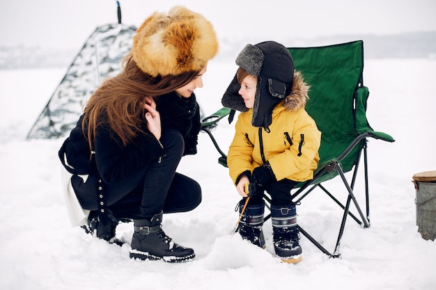 Mooie vrouwenzitting op de winter die met zoon vissen