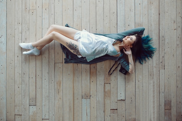 Mooie zorgeloze jonge casual vrouw liggend op de houten vloer