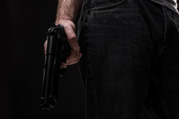 Gratis foto moordenaar met pistool op zwarte achtergrond in de studio