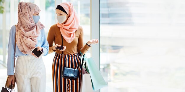 Moslimmeisjes in gezichtsmasker winkelen in het winkelcentrum in het nieuwe normaal