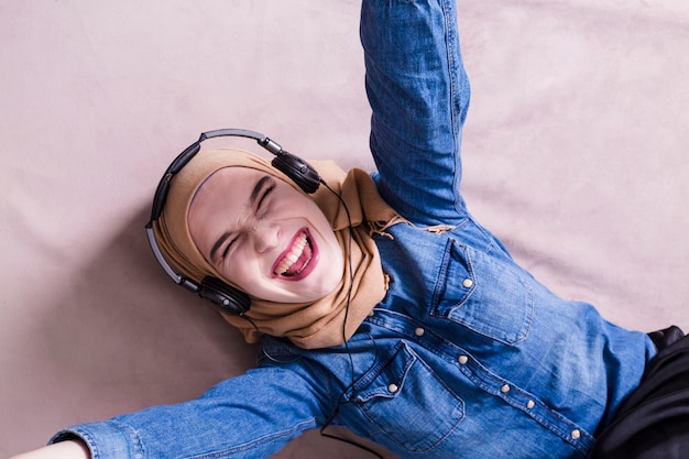 Moslimvrouw die aan muziek op hoofdtelefoons luistert