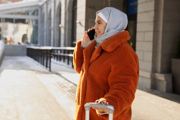 Moslimvrouw die het hotel verlaat en op haar smartphone praat terwijl ze op vakantie is