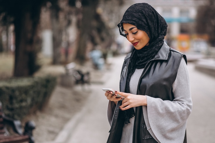 Gratis Foto moslimvrouw die telefoon buiten in de straat met behulp van