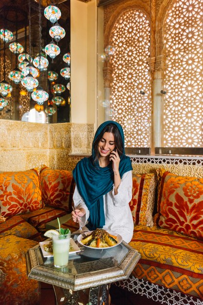 Moslimvrouw die telefoongesprek in restaurant maken