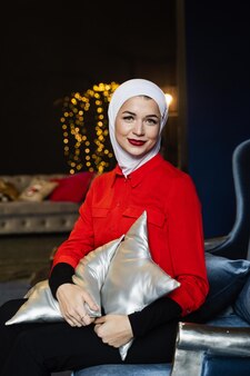 Moslimvrouw in de buurt van kerstversiering in studio. professioneel moslimmodel poseren op oudejaarsavond