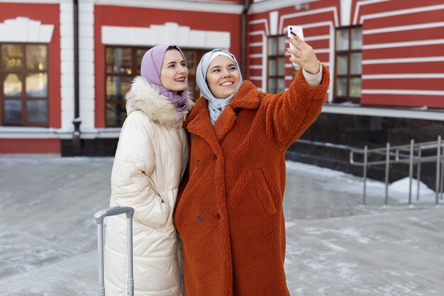 Moslimvrouwen die een selfie maken met een smartphone terwijl ze op vakantie zijn