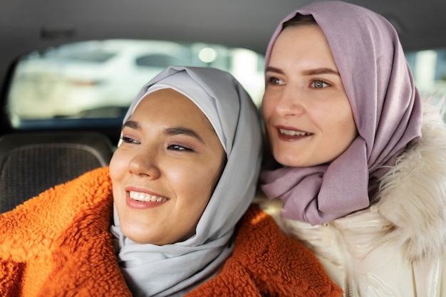 Moslimvrouwen glimlachen en verkennen de stad met een auto terwijl ze op vakantie zijn