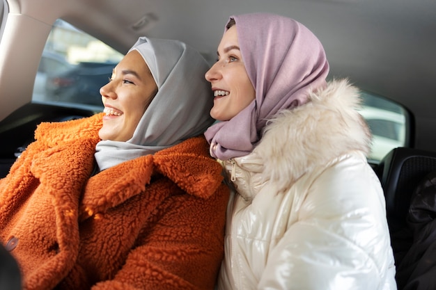 Moslimvrouwen glimlachen en verkennen de stad met een auto terwijl ze op vakantie zijn