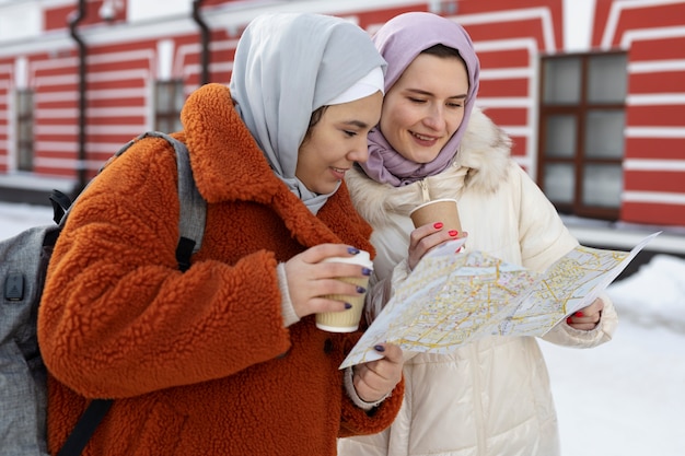 Moslimvrouwen met hijabs die koffie drinken en een kaart raadplegen terwijl ze op vakantie zijn