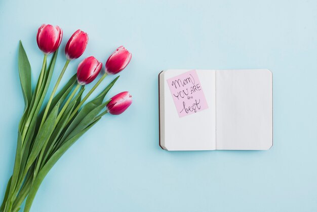 Mother&#39;s Day achtergrond met tulpen naast een lege notebook