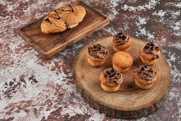 Muffins en croissants op een houten bord.