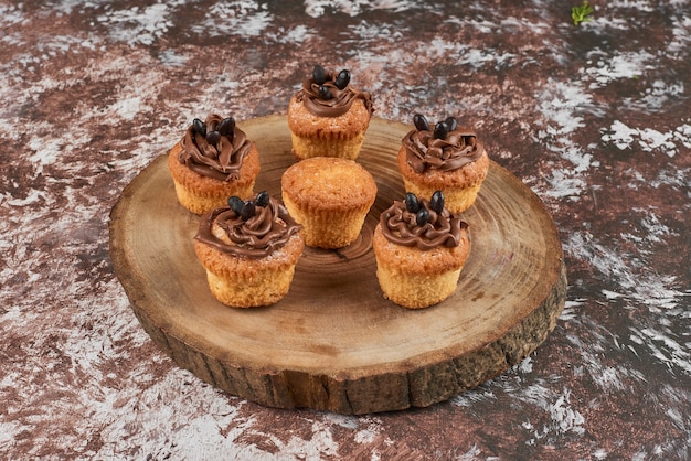 Muffins met cacaoroom op een houten bord.