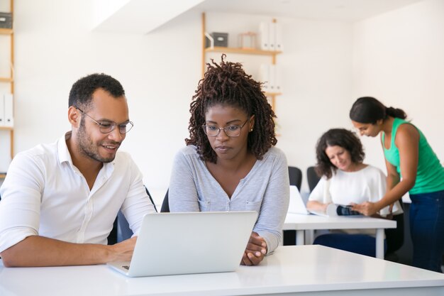 Multi-etnische collega's die laptop het scherm bekijken